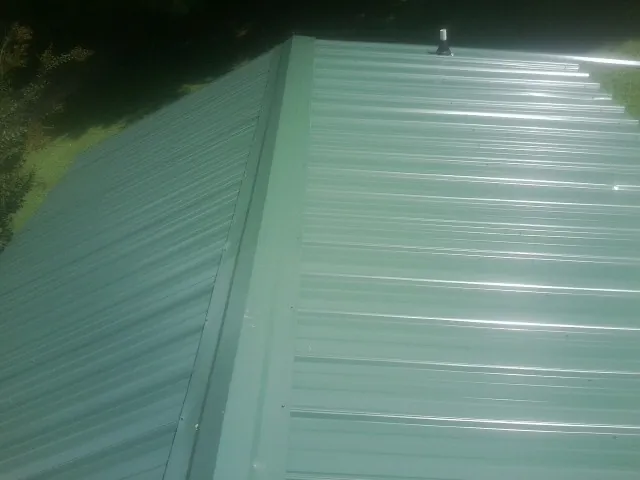 New green metal panels meeting at the ridge of a roof — Flat Roof Repair work by our crew in Bristol